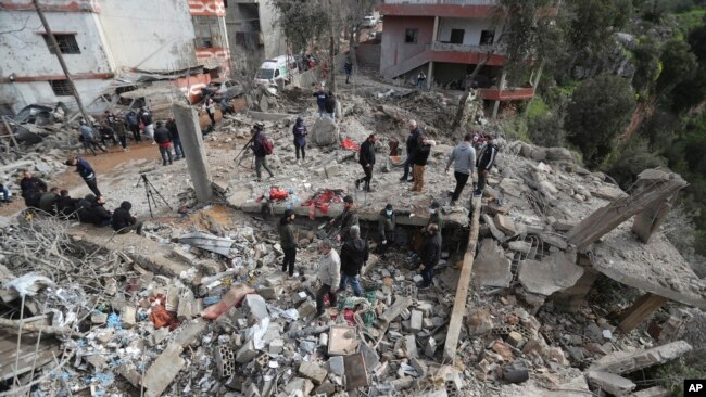 La gente se reúne entre los escombros de un centro paramédico que fue destruido por un ataque aéreo israelí la madrugada del miércoles en la aldea de Hebbariye, en el sur del Líbano, el 27 de marzo de 2024.