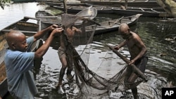 Fishermen sort out their fishing net at the bank of a polluted river in Bidere community in Ogoniland in Nigeria's delta region, August 20, 2011.