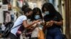 FILE - Women use their phones in a street in Havana, July 14, 2021.