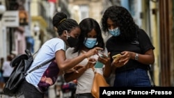 FILE - Women use their phones in a street in Havana, July 14, 2021.