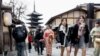 Turis berjalan di jalanan dekat Pagoda Yasaka (belakang) saat berkunjung ke kota Kyoto, 13 Januari 2025. (PAUL MILLER / AFP)