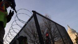 Workers install razor wire atop the unscalable fence surrounding the U.S. Capitol in the wake of the January 6th riot and ahead of the upcoming inauguration in Washington, Jan. 14, 2021.