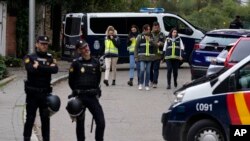 Policías montan guardia mientras otros agentes con chalecos amarillos recorren la zona acordonada cerca a la embajada de Ucrania en Madrid, España, el miércoles 30 de noviembre de 2022