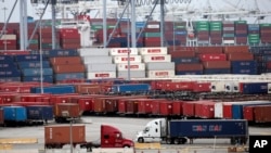 FILE - Two trucks move shipping containers at the Port of Long Beach in Long Beach, California, Feb. 17, 2015.