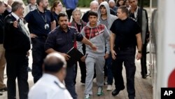 FILE - Two unidentified young migrants get off a bus as they arrive at Lunar House, which houses the headquarters of UK Visas and Immigration in Croydon, south London. 