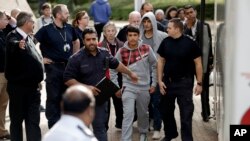 FILE - Two unidentified young migrants get off a bus as they arrive at Lunar House, which houses the headquarters of UK Visas and Immigration in Croydon, south London, Monday, Oct. 17, 2016. 