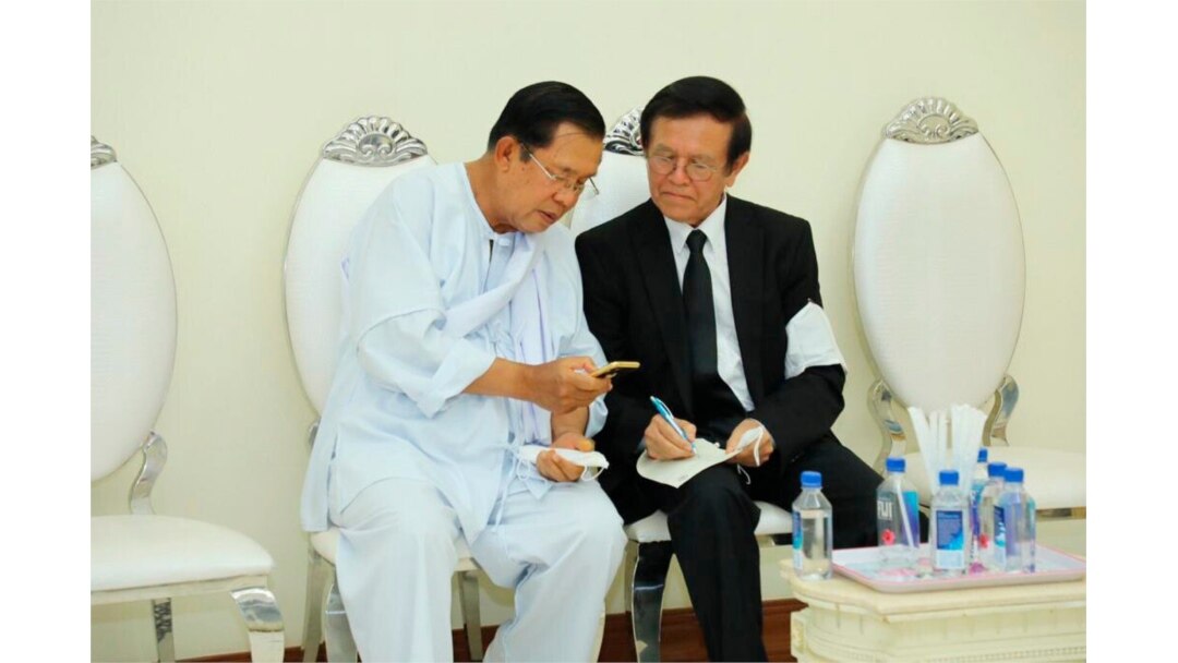 Perdana Menteri Kamboja Hun Sen, kiri, berbicara dengan oposisi utama yang dibubarkan, pemimpin Partai Penyelamat Nasional Kamboja Kem Sokha pada upacara berkabung untuk ibu mertua Sen, di Phnom Penh, Kamboja, 5 Mei 2020. (Foto: AP)