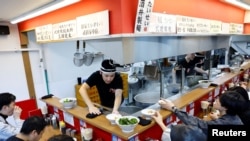 An employee serves to customers at Menya Taisei, a ramen shop, in Tokyo, Japan, October 22, 2024.