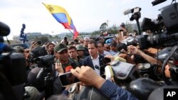 Pemimpin oposisi Venezuela yang memproklamirkan diri sebagai Presiden Sementara, Juan Guaido (tengah) memberi keterangan kepada pers dan pendukungnya di luar pangkalan udara La Carlota, Caracas, Venezuela, 30 April 2019.