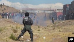 Independent miners clash with the police as they run from clouds of tear gas during protests in Panduro, Bolivia, Thursday, Aug. 25, 2016.