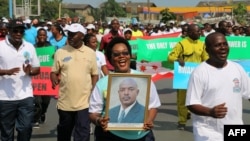 FILE - A woman holds up a picture of Burundi's President Pierre Nkurunziza during a rally in Bujumbura on May 14, 2016, commemorating the one-year anniversary of what government supporters see as a failed coup attempt.