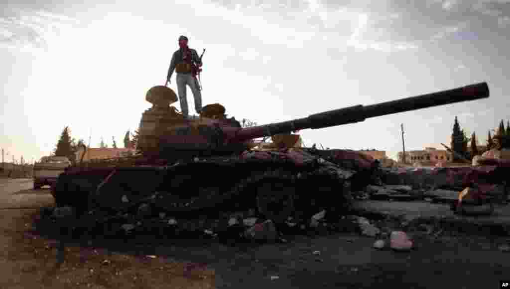 This citizen journalism image provided by The Syrian Revolution against Bashar Assad shows a Free Syrian army fighter on a damaged military tank in Zabadani, near Damascus, Sept. 8, 2013.