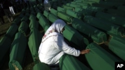 A woman touches the coffin of her relative among the over 600 displayed at the Potocari memorial cemetery near Srebrenica, some 160 kilometers east of Sarajevo, Bosnia-Herzegovina, July 11, 2011