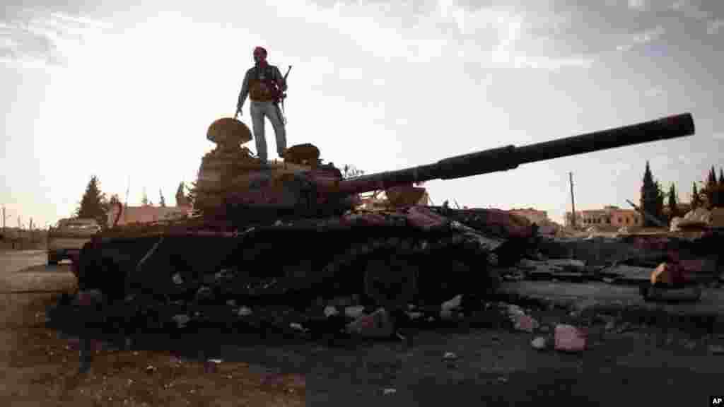 This citizen journalism image provided by The Syrian Revolution against Bashar Assad shows a Free Syrian army fighter on a damaged military tank in Zabadani, near Damascus, Sept. 8, 2013.