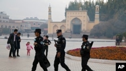 FILE - Uyghur security workers walk near the Id Kah Mosque in Kashgar in western China's Xinjiang region, Nov. 4, 2017. 