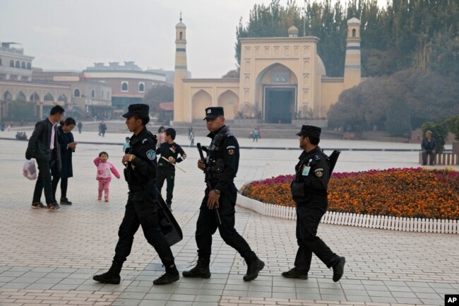 FILE - Uighur security personnel patrol near the Id Kah Mosque in Kashgar in western China's Xinjiang region, Nov. 4, 2017.