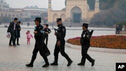 FILE - Uighur security personnel patrol near the Id Kah Mosque in Kashgar, Xinjiang, Nov. 4, 2017. 