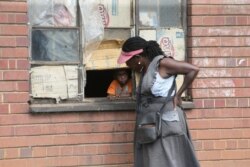 A woman talks to a child through a window in Harare, May 28, 2020. Manhunts have begun after hundreds of people, some with the coronavirus, fled quarantine centers in Zimbabwe and Malawi.