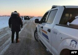 FILE - This handout photo released Jan. 20, 2022, by the Royal Canadian Mounted Police in Emerson, Manitoba, shows officers on the scene near the Canada-U.S. border.
