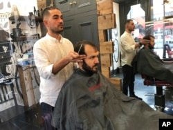Rado Asatrian cuts a customer's hair at Man-oj hair salon in London's financial district, Thursday, September 9, 2021. Before COVID-19, Asatrian usually had 10 to 15 customers a day, but now it’s down to three or four. (AP Photo/Kelvin Chan)