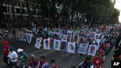 Para kerabat memegang poster bergambar 43 mahasiswa yang hilang dalam protes di Mexico City (5/11). (AP/Marco Ugarte)