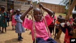 FILE - In this June 1, 2017 file photo, Abdu Kabanda, 6, who is HIV-positive and receiving HIV treatment from a Ugandan support group, plays on a swing at the Jovia nursery and primary school in Kyanangazi village, Uganda.