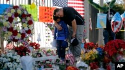 Gary Mendoza, and his son Michael pay their respects at a makeshift memorial site honoring Wednesday's shooting victims Monday, Dec. 7, 2015, in San Bernardino, California.