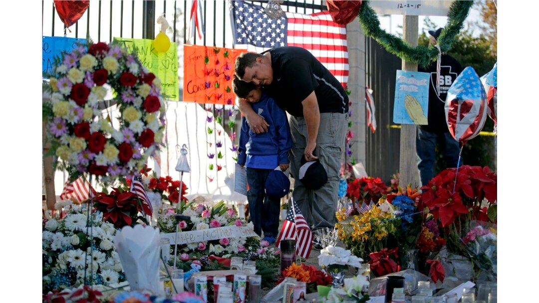 FILE - Gary Mendoza and his son Michael pay their respects at a makeshift memorial site honoring shooting victims in San Bernardino, California, Dec. 7, 2015.