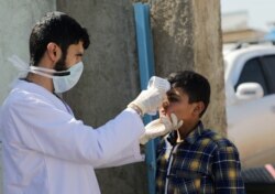 A health worker tests a Syrian boy as part of measures to control the coronavirus, in Azaz, Syria, March 11, 2020.