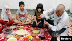 Seorang pria menuangkan jus kismis untuk keluarganya saat bersiap berbuka puasa di bulan suci Ramadan di Mosul Irak, 18 April 2021. (REUTERS / Khalid Al-Mousily)
