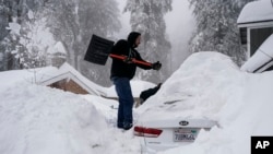 FILE - A man shovels snow around his car in Running Springs, California, Feb. 28, 2023.