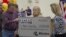Mark, left, and Cindy, center, Hill are presented a check by a Missouri Lottery official during the announcement of Powerball winners in Dearborn, Missouri, November 30, 2012. 