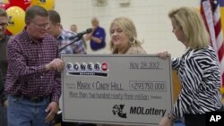 Mark, left, and Cindy, center, Hill are presented a check by a Missouri Lottery official during the announcement of Powerball winners in Dearborn, Missouri, November 30, 2012. 