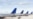 FILE - The tails of airplanes sitting at gates to an airport.