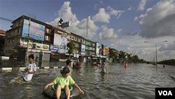 Seorang perempuan Thailand menggunakan pelampung untuk meninggalkan daerah banjir di Bangkok, Rabu (26/10).