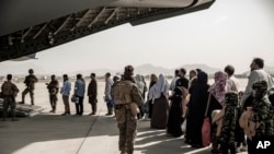 FILE - In this image provided by the U.S. Marine Corps, evacuees wait to board a Boeing C-17 Globemaster III during an evacuation at Hamid Karzai International Airport in Kabul, Afghanistan, Aug. 30. 2021.
