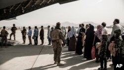 FILE - In this image provided by the U.S. Marine Corps, evacuees wait to board a Boeing C-17 Globemaster III during an evacuation at Hamid Karzai International Airport in Kabul, Afghanistan, Aug. 30. 2021.