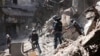 Donetsk People Republic Emergency Situations Ministry employees clear rubble at the side of the damaged Mariupol theater building during heavy fighting in Mariupol, in territory under the government of the Donetsk People's Republic, eastern Ukraine, May 1