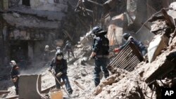 Donetsk People Republic Emergency Situations Ministry employees clear rubble at the side of the damaged Mariupol theater building during heavy fighting in Mariupol, in territory under the government of the Donetsk People's Republic, eastern Ukraine, May 1