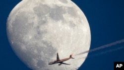 Siluet Airbus A330 milik perusahaan Air China yang terbang menuju Beijing terlihat di dekat Bulan saat terbang di atas St. Petersburg, Rusia, 13 April 2022. (Foto: AP)