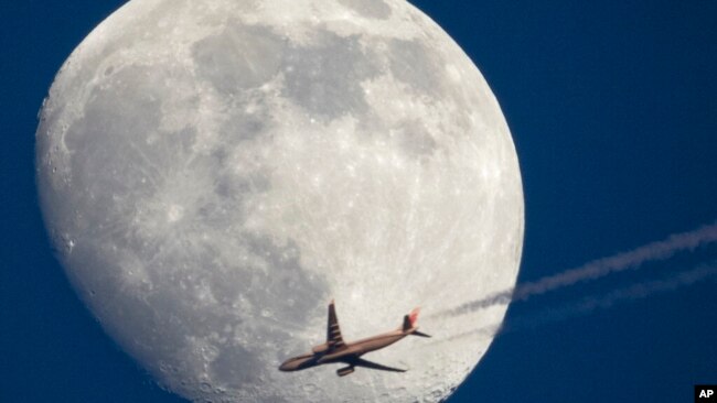 Airbus A330 of Air China company flying from Frankfurt to Beijing is silhouetted against the moon as it flies over St. Petersburg, Russia, April 13, 2022.