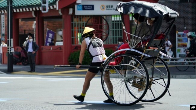 FILE - A rickshaw puller carries tourists near Sensoji Buddhist temple at Tokyo's Asakusa district in Tokyo, March 31, 2021. (AP Photo/Eugene Hoshiko, File)