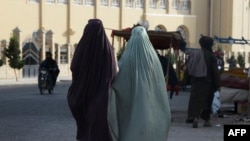 FILE - Burqa-clad women walk along a street in Kandahar on May 7, 2022.