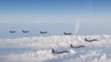 Tiga pesawat tempur F-15 Angkatan Bela Diri Jepang, depan, dan empat pesawat tempur F-16 Angkatan Bersenjata AS terbang di atas Laut Jepang pada Rabu, 25 Mei 2022. (Foto: AP)