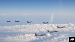 Tiga pesawat tempur F-15 Angkatan Bela Diri Jepang, depan, dan empat pesawat tempur F-16 Angkatan Bersenjata AS terbang di atas Laut Jepang pada Rabu, 25 Mei 2022. (Foto: AP)