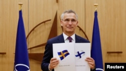 옌스 스톨텐베르그 북대서양조약기구(NATO·나토) 사무총장이 18일 스웨덴(왼쪽)과 핀란드의 가입 신청서를 들고 기념촬영하고 있다. 