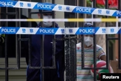 FILE - Residents look out through gaps in the barriers at a closed residential area during lockdown, amid the COVID-19 outbreak, in Shanghai, China, May 17, 2022.