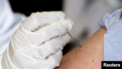 ARCHIVO. La Dra. Marcia Trape del Centro de Salud de la Universidad de Connecticut empuja la aguja de inmunización de la vacuna contra la viruela quince veces en el brazo del Dr. Richard Garibaldi frente a los medios de comunicación el 24 de enero de 2003 .