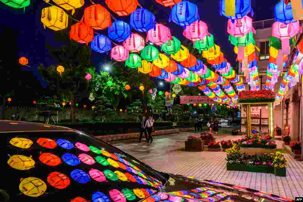 Pedestrians walk past a display of lotus lanterns outside the Beomnyeonsa Temple, a Buddhist temple in Seoul, South Korea.