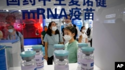 Visitors look at giant replica bottles of COVID-19 vaccine using mRNA technologies at the China International Fair for Trade in Services in Beijing, China, Sept. 5, 2021. More than two years into the pandemic, China has not approved the mRNA vaccines.